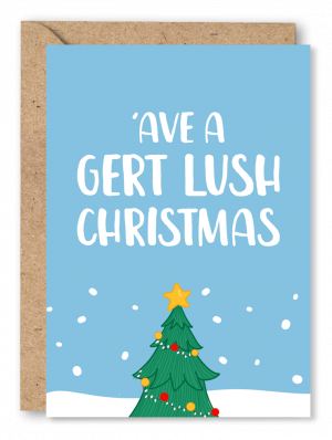 A light blue Christmas card featuring the top of a Christmas tree at the bottom of the card, on a snowy background and white text at the top which reads ‘’ave a gert lush Christmas’